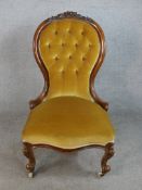 A late Victorian walnut framed spoon back nursing chair raised on cabriole supports terminating in