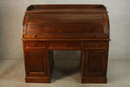 A 20th polised hardwood twin pedestal roll top desk, opening to reveal fitted interior above three