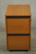 A contemporary teak two drawer filing cabinet on wheels. H.67 W.42 D.60cm.