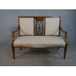 An Edwardian walnut and marquetry inlaid two seater settee, with a pierced back splat and open arms,