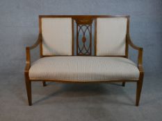 An Edwardian walnut and marquetry inlaid two seater settee, with a pierced back splat and open arms,