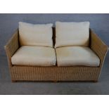 A contemporary two seater wicker conservatory sofa with loose cushions raised on block feet. H.72