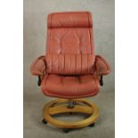 A 20th century Scandinavian design red leather and teak swivel chair raised on circular base on