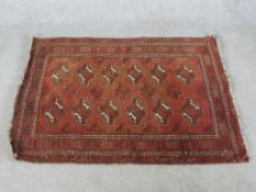 A 20th century handmade Persian Turkaman red ground rug with central lozenge design within geometric