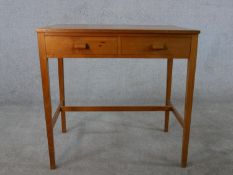 A mid 20th century teak two drawer side table, on square section legs joined by H stretchers. H.76