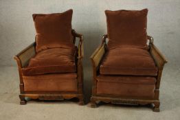 A pair of early 20th century carved mahogany framed and bergère armchairs, each with scroll arms and