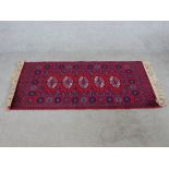 A 20th century red ground Bakora rug with four central lozenges. L.68 W.132cm.