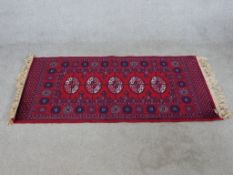 A 20th century red ground Bakora rug with four central lozenges. L.68 W.132cm.