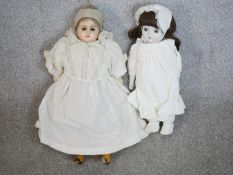 Two 19th century dolls, one craved and painted in a lace bonnet and dress with glass eyes, the other