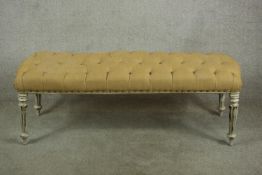 A 20th century painted rectangular wooden seat with yellow quilted padded cushion, raised on