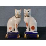 A pair of Staffordshire style pottery cats, each seated on a cobalt blue cushion with gilt