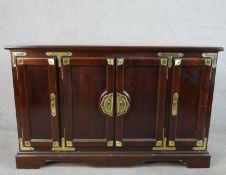 A 20th century Chinese style hardwood four door sideboard with brass mounts, the central cupboards