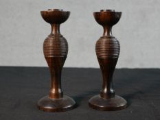 A pair of 20th century ring turned hardwood candlesticks, with baluster stems and on circular