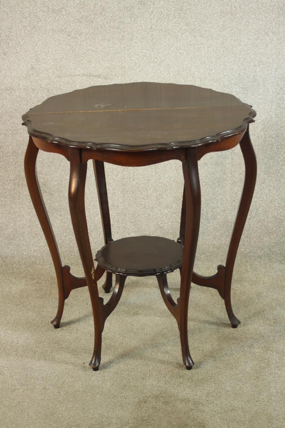 A late Victorian mahogany two tier occasional table, raised on six cabriole supports terminiating in