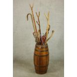 A brass coopered barrel form umbrella stand and a collection of eleven walking sticks and two