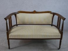 An Edwardian inlaid mahogany open arm and pierced splat back settee, with stuff over seat, raised on