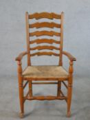 A late 19th century beech framed open arm ladder back chair, with straw seat, raised on turned