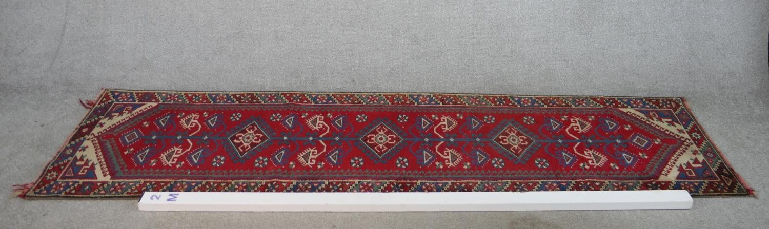 A 20th century red ground Heriz style runner with three central diamond lozenges within a - Image 2 of 4