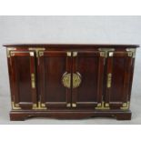 A 20th century Chinese style hardwood four door sideboard with brass mounts, the central cupboards