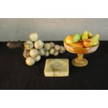 A collection of carved onyx and marble items, including fruit in a bowl with selection of dyed