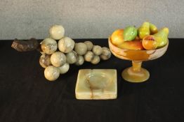 A collection of carved onyx and marble items, including fruit in a bowl with selection of dyed