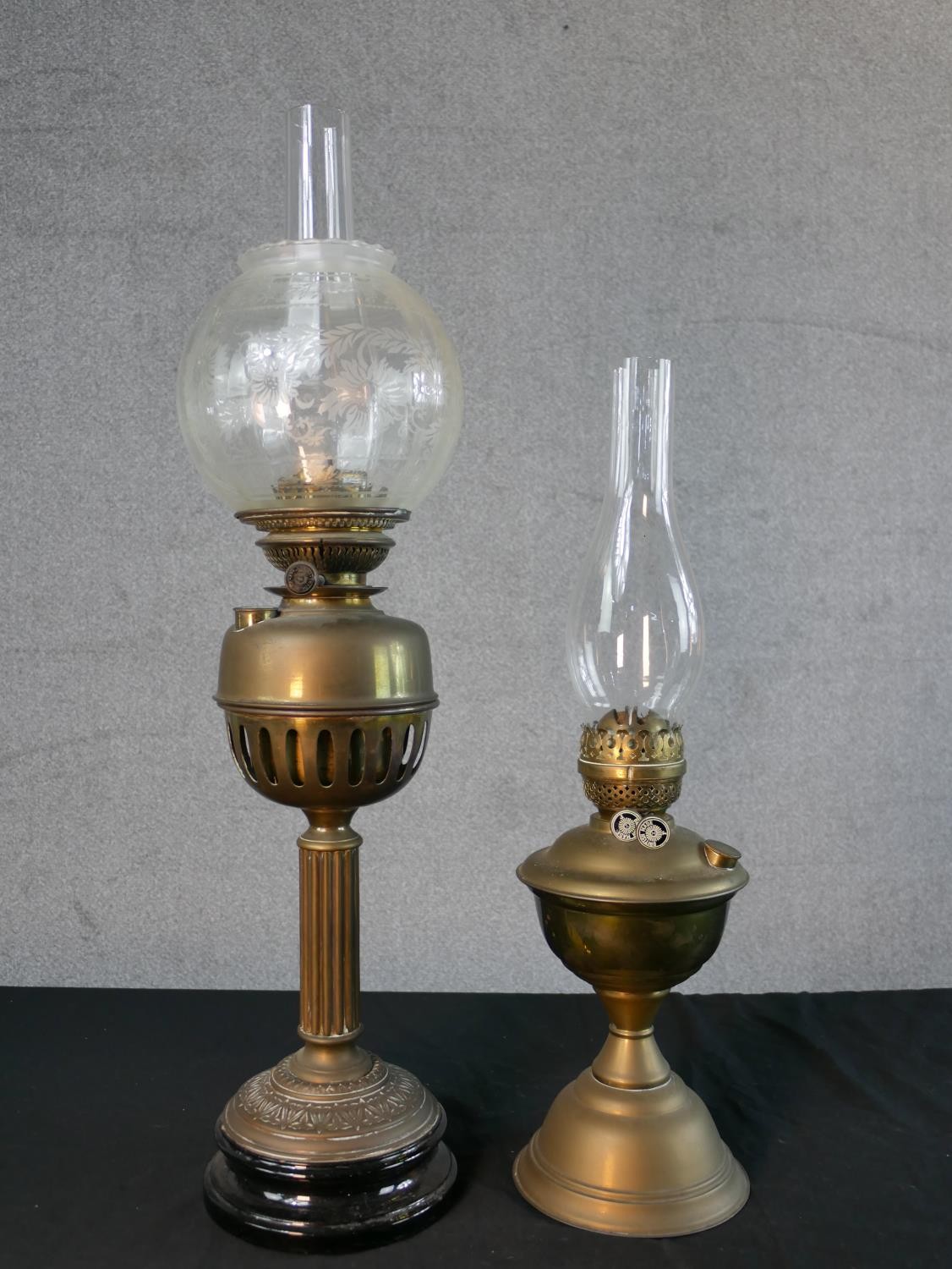 Three Victorian brass oil lamps, one with a spherical etched glass shade and a glass funnel, on an