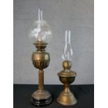 Three Victorian brass oil lamps, one with a spherical etched glass shade and a glass funnel, on an