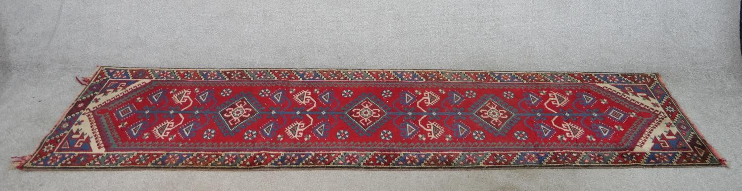 A 20th century red ground Heriz style runner with three central diamond lozenges within a