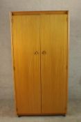 A 1960s Schreiber teak wardrobe with a pair of doors, opening to reveal hanging space and