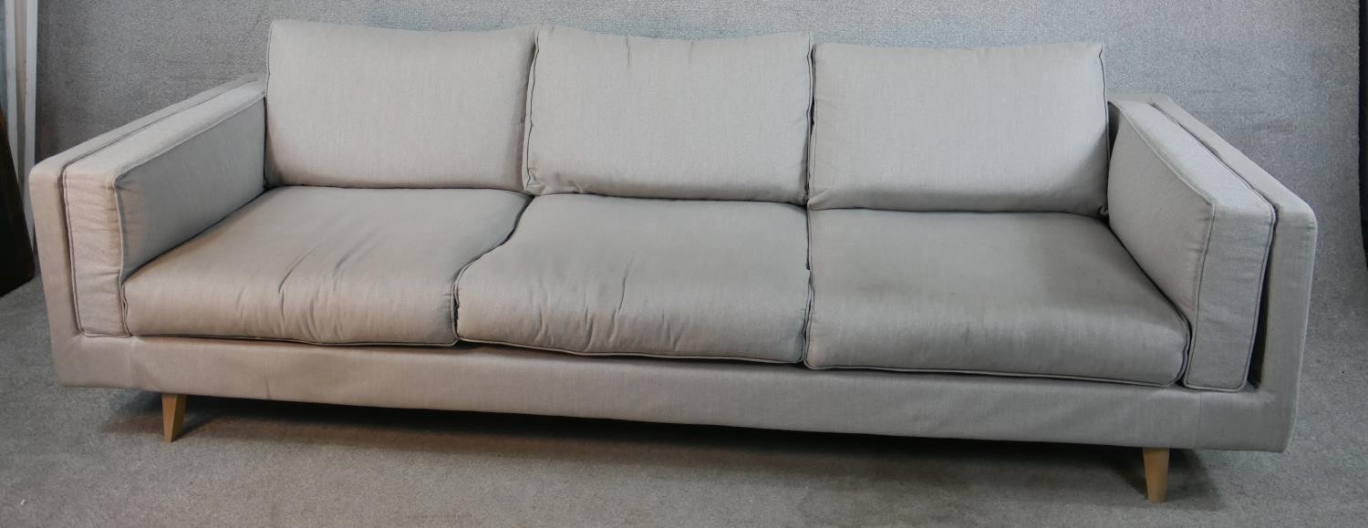 A contemporary three seater Calligaris settee, upholstered in grey fabric raised on shaped beech