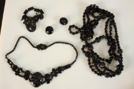 A collection of carved jet and black glass jewellery, including a carved stylised foliate design