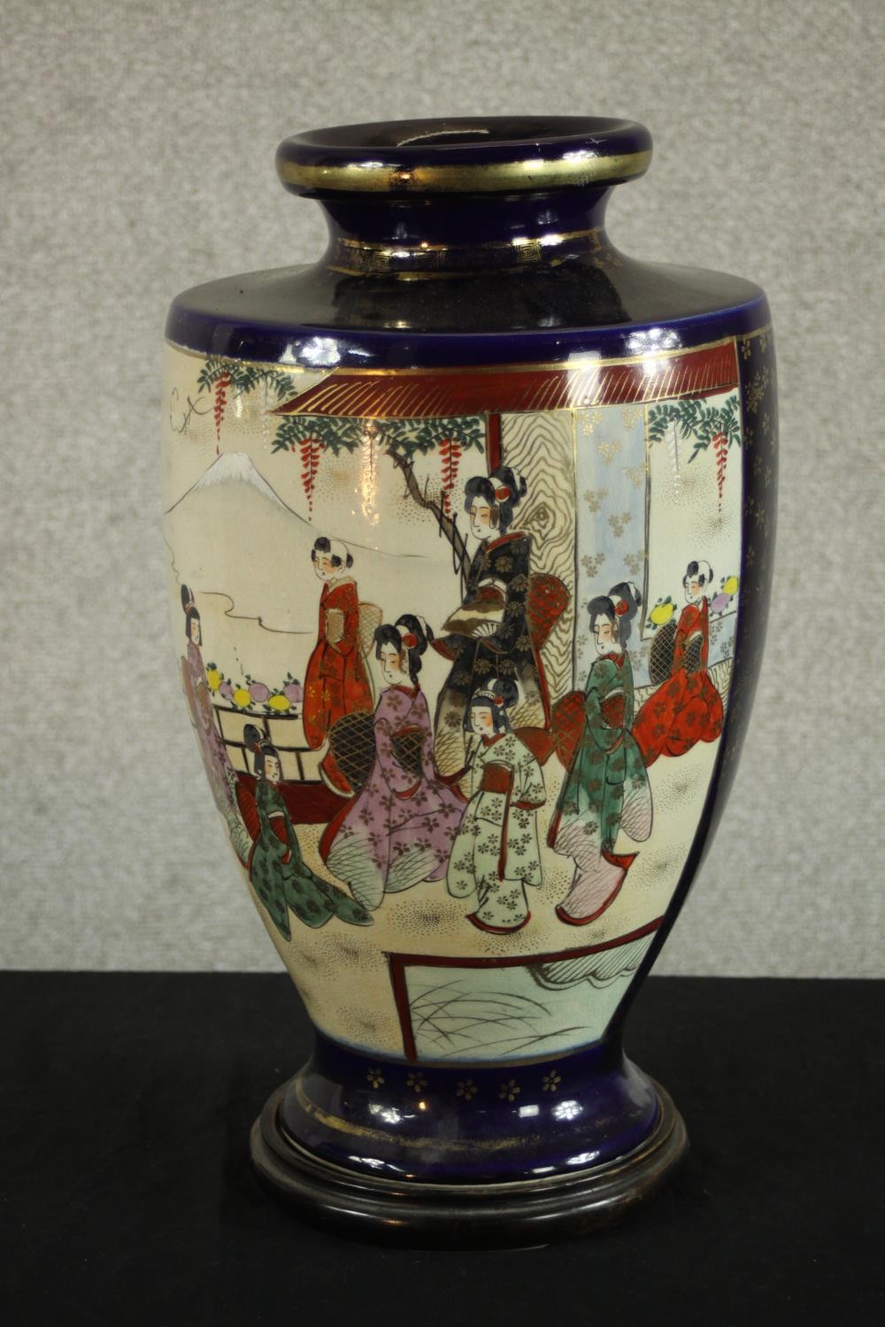 A mid Japanese Satsuma pottery vase, decorated with figures in a temple with Mount Fuji behind,
