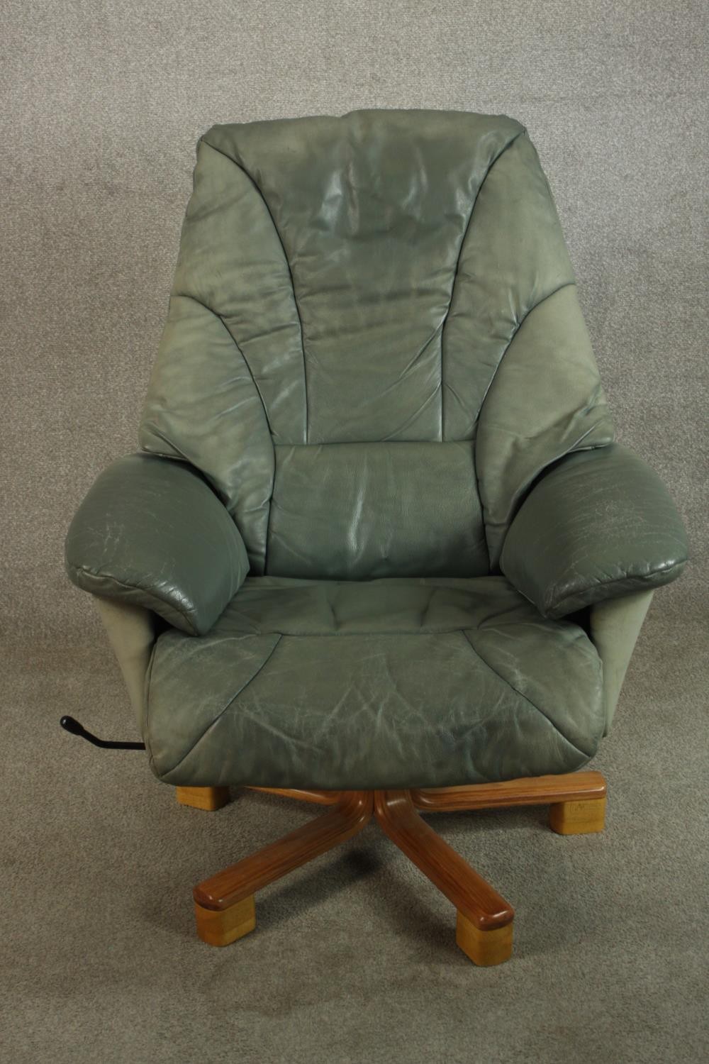 A 20th century pale green leather swival and counter leaver arm chair raised on five splayed