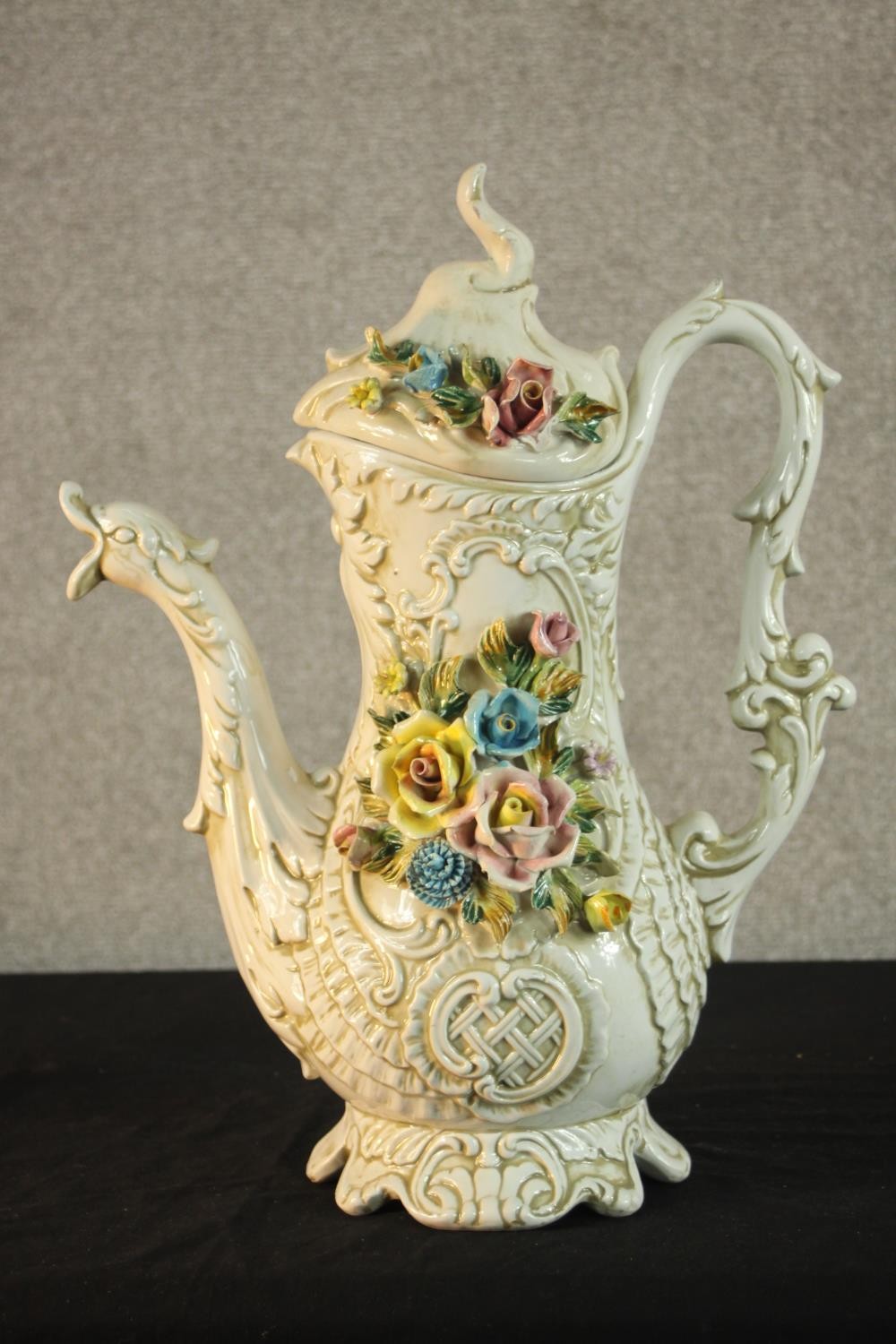 A 20th century Capodimonte pottery floral encrusted jug, the moulded hand in the form of vines and