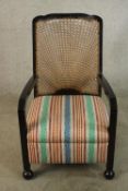 An early 20th century bergere backed open armchair, with sloping fabric covered seat raised on