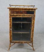 A 19th century Aesthetic style bamboo and lacquer single glass door bookcase, raised on splayed