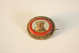 A grand tour micro mosaic brooch/pendant depicting a classical ruin with a red hard stone border