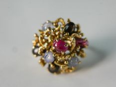 A 14 carat yellow gold and ruby and star sapphire abstract form dress ring. The ring set three