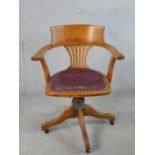 An early 20th century oak framed Captains style open arm desk chair, with rotating seat raised on