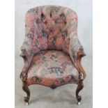 A 19th century mahogany framed upholstered spoon back armchair raised on carved cabriole supports