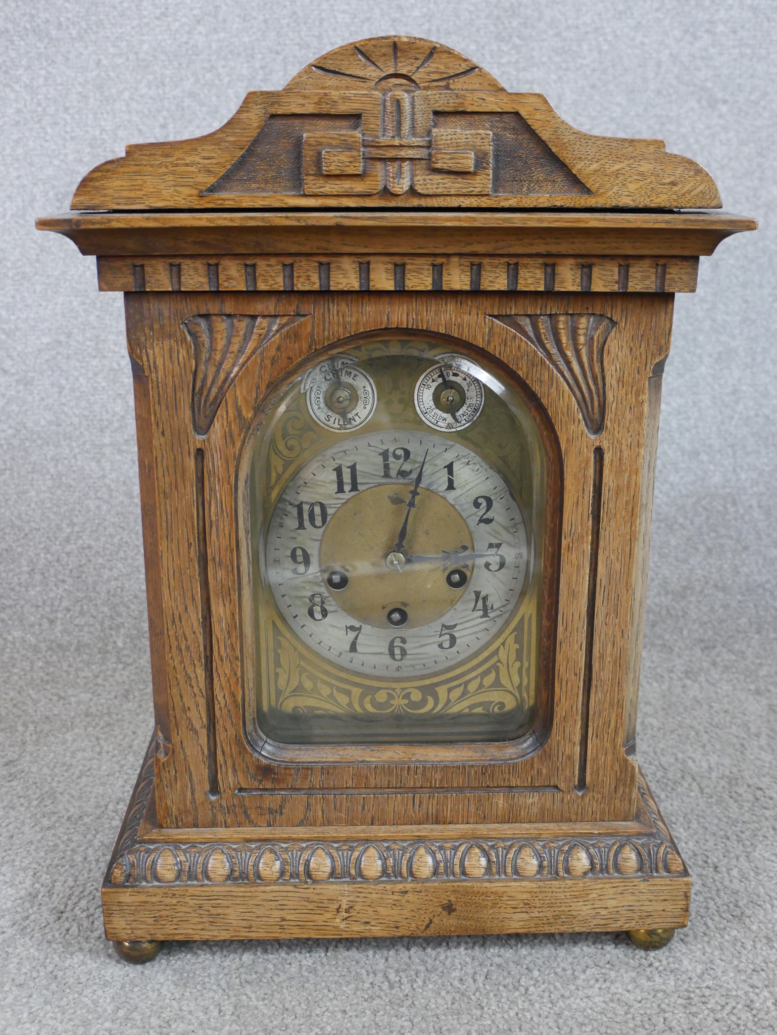 A late 19th/early 20th century carved oak mantle clock, the brass dial with black Arabic numerals,