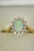 A boxed contemporary 18ct white and yellow gold opal and diamond cluster ring. Set to centre with an