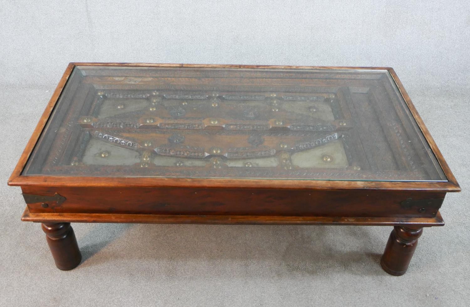 A 20th century carved hardwood, possibly African 'shield' inset rectangular glass topped coffee