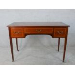 An Edwardian inlaid mahogany three drawer dressing table raised on tapering supports terminating