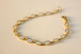 A 9ct Opal cabochon articulated bracelet. Set with sixteen oval opal cabochons in open back