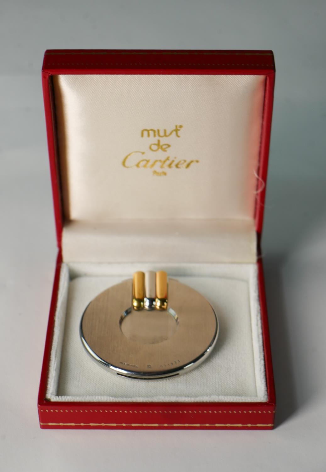 A late 20th century circular brushed steel Cartier cigar cutter, with bi-colour handle, impressed
