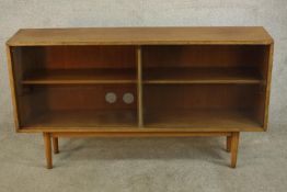 A mid 20th century teak bookcase, with two glass sliding doors, raised on tapering supports. H.76