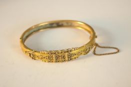 A Victorian yellow metal (tests as 9ct) Etruscan style filigree wire work clip bangle with safety