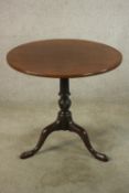 A George III mahogany tilt top tripod table, with turned central column raised on three outswept