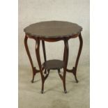 A late Victorian mahogany two tier occasional table, raised on six cabriole supports terminating in
